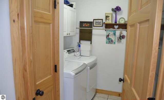 102 James Sq, Roscommon, MI 48653 - laundry room featuring cabinet space, washer and dryer, light tile patterned floors, and baseboards