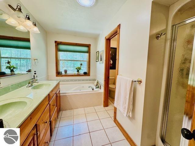 102 James Sq, Roscommon, MI 48653 - bathroom with toilet, a stall shower, a garden tub, tile patterned floors, and double vanity