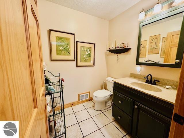 102 James Sq, Roscommon, MI 48653 - half bathroom with toilet, tile patterned floors, vanity, and baseboards