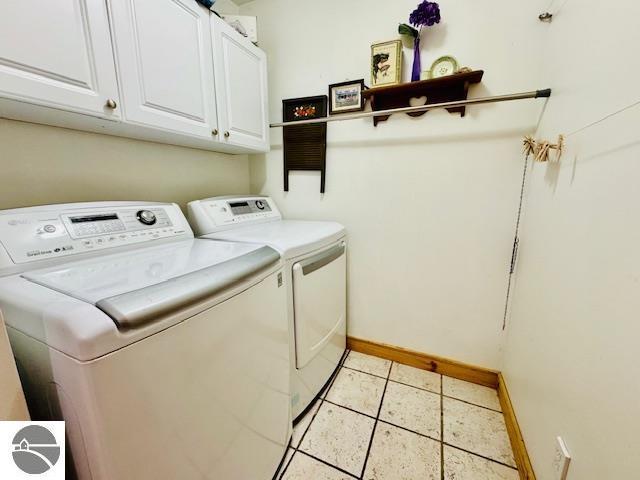 102 James Sq, Roscommon, MI 48653 - laundry room featuring independent washer and dryer, cabinet space, baseboards, and light tile patterned floors