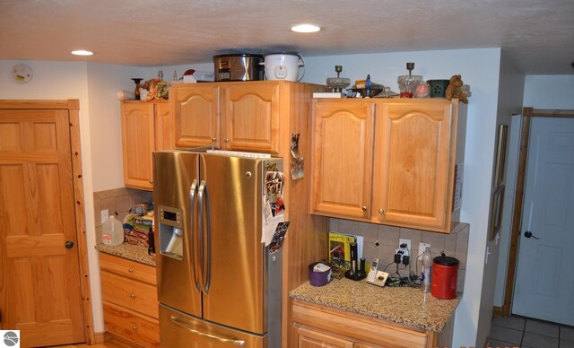 102 James Sq, Roscommon, MI 48653 - kitchen with stainless steel fridge with ice dispenser, tasteful backsplash, light stone counters, light tile patterned flooring, and recessed lighting