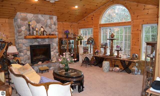 102 James Sq, Roscommon, MI 48653 - living room with healthy amount of natural light, wood walls, lofted ceiling, carpet, and a stone fireplace