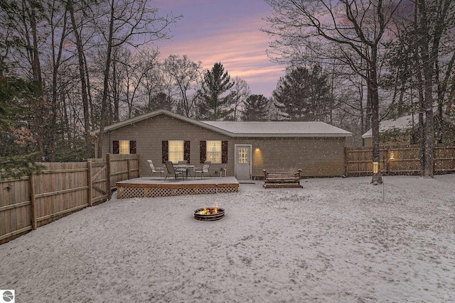 back of property at dusk featuring a fenced backyard, an outdoor fire pit, and a wooden deck
