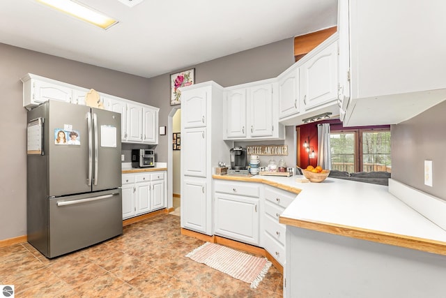 kitchen with freestanding refrigerator, white cabinets, and light countertops