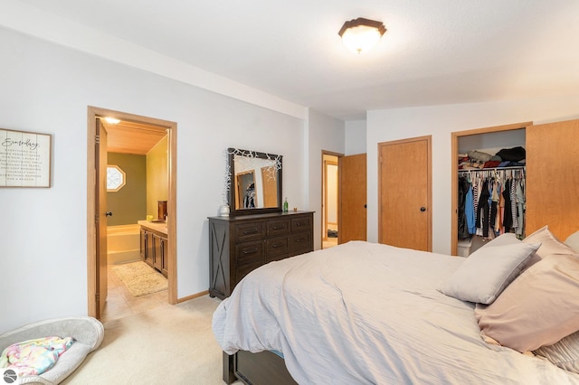 bedroom with baseboards, connected bathroom, and light carpet