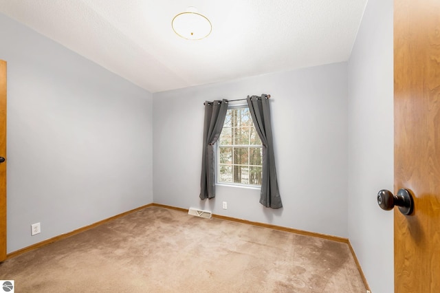 spare room featuring baseboards, visible vents, and carpet floors