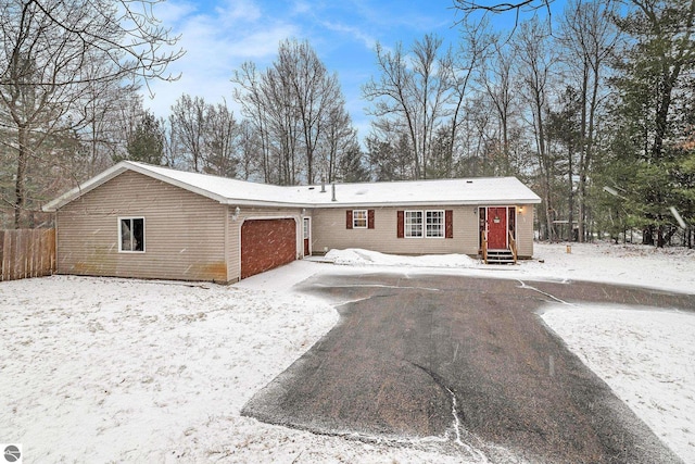 snow covered house with a garage, fence, and entry steps