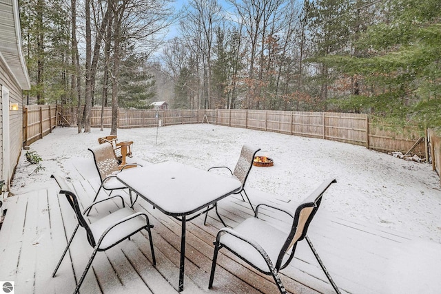 snow covered deck featuring outdoor dining area and a fenced backyard
