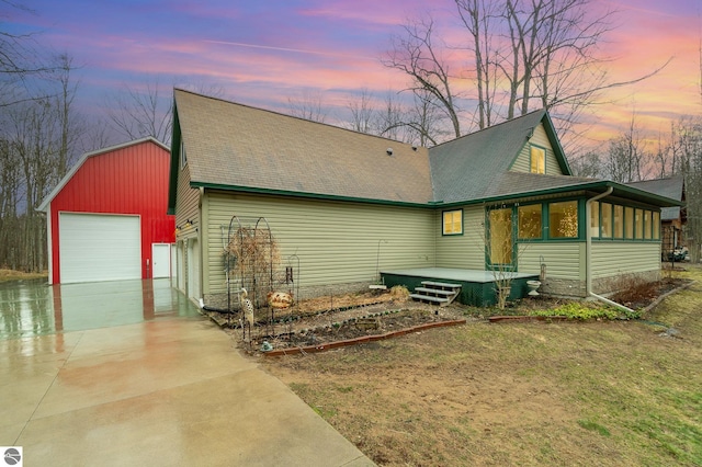 view of front of house featuring driveway, a shingled roof, and an outbuilding