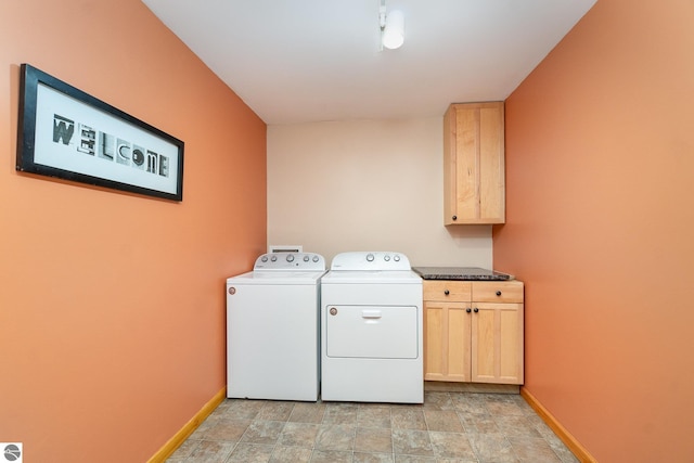 laundry area featuring cabinet space, washing machine and dryer, baseboards, and stone finish floor