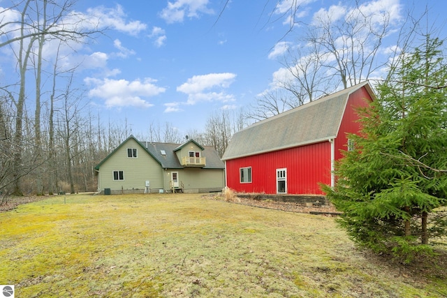 rear view of house with a gambrel roof, an outdoor structure, a barn, and a yard