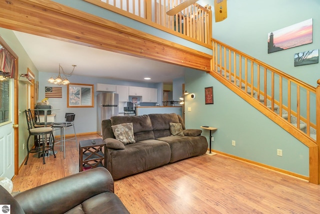 living room featuring an inviting chandelier, baseboards, stairs, and wood finished floors