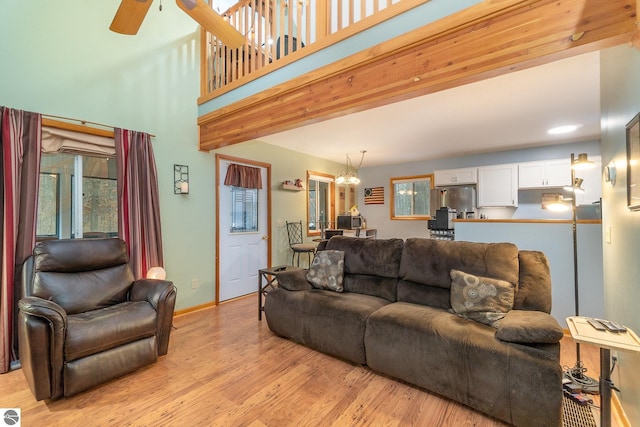 living area with plenty of natural light, ceiling fan with notable chandelier, baseboards, and light wood-type flooring