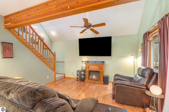 living room with stairway, baseboards, ceiling fan, a glass covered fireplace, and wood finished floors