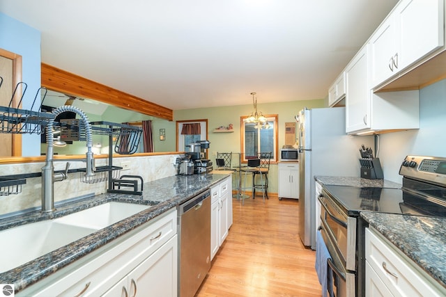 kitchen featuring a notable chandelier, a sink, light wood finished floors, appliances with stainless steel finishes, and white cabinets
