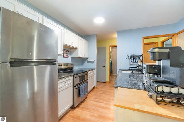 kitchen featuring white cabinetry, light wood-style floors, dark stone counters, and stainless steel appliances