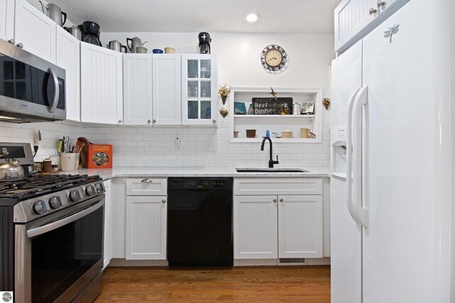 112 N Benzie Blvd, Beulah, MI 49617 - kitchen featuring white cabinets, a sink, stainless steel appliances, and tasteful backsplash