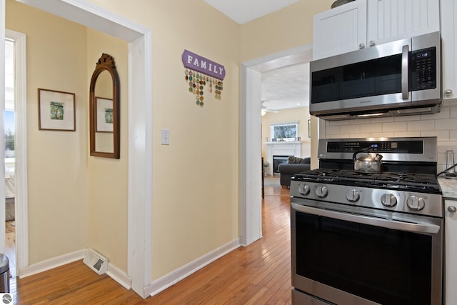 112 N Benzie Blvd, Beulah, MI 49617 - kitchen with stainless steel appliances, baseboards, tasteful backsplash, and light wood finished floors