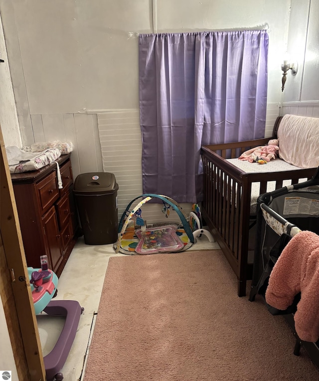 bedroom featuring a decorative wall and wainscoting