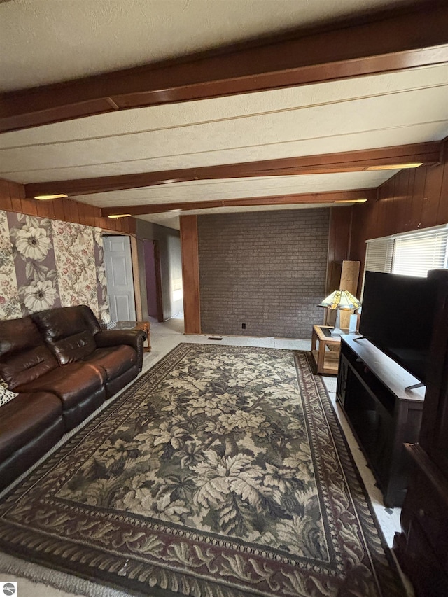 living room featuring beam ceiling and brick wall
