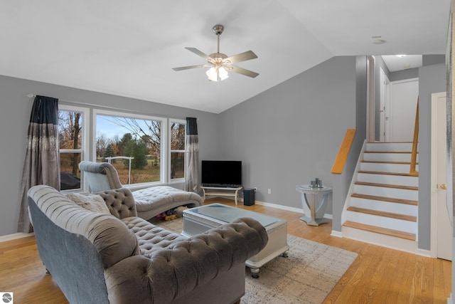 living area featuring vaulted ceiling, stairway, a ceiling fan, light wood finished floors, and baseboards