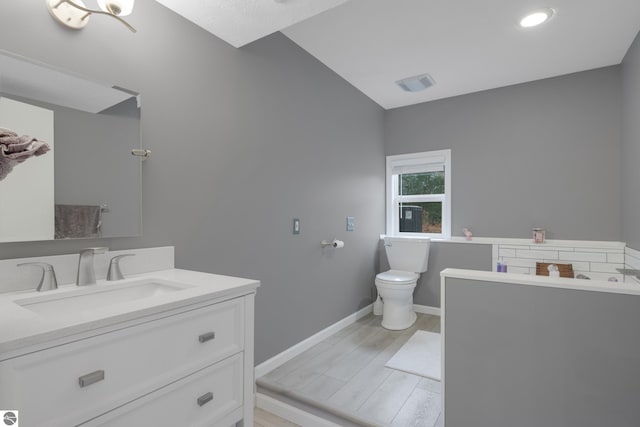 full bath with toilet, vanity, wood finished floors, baseboards, and visible vents