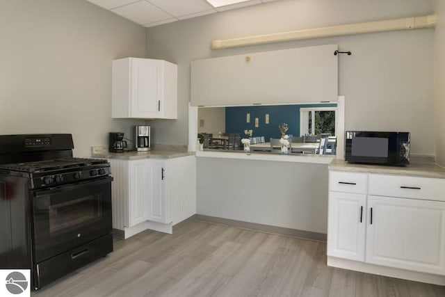 4548 Goldenrod Dr, Traverse City, MI 49686 - kitchen with black appliances, light wood-type flooring, a drop ceiling, white cabinetry, and light countertops