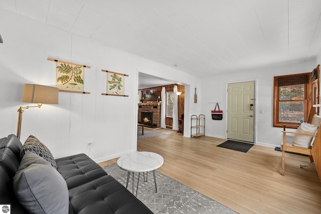 living room featuring baseboards, light wood-style floors, and a fireplace