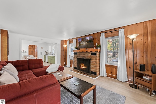 living area featuring a fireplace, wood walls, and light wood finished floors