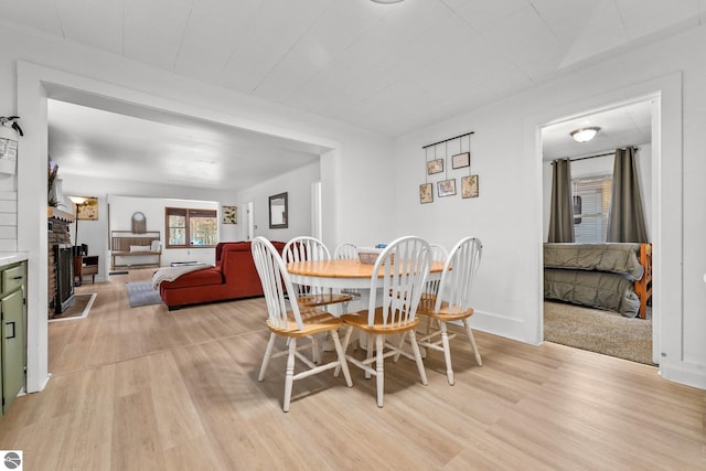 dining room featuring baseboards, a fireplace, and light wood-style flooring