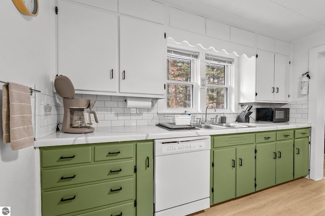 kitchen with light countertops, a sink, black microwave, white dishwasher, and backsplash
