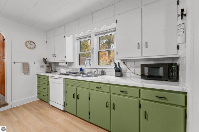 kitchen with light wood finished floors, dishwasher, a sink, black microwave, and backsplash
