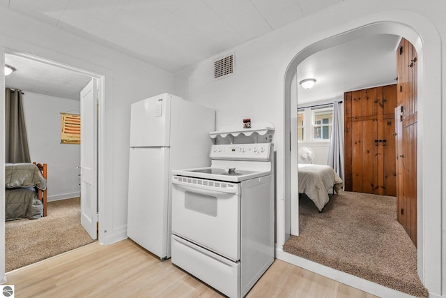 kitchen featuring visible vents, arched walkways, light wood-style floors, and white appliances