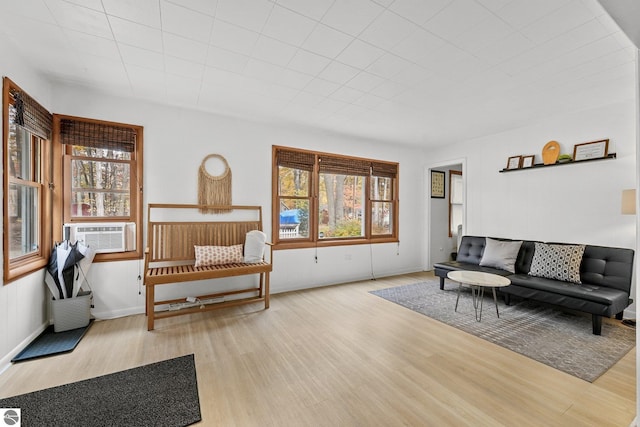 living area with cooling unit, a healthy amount of sunlight, and wood finished floors