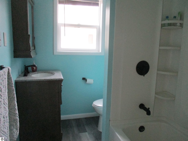bathroom with washtub / shower combination, vanity, baseboards, toilet, and wood finished floors