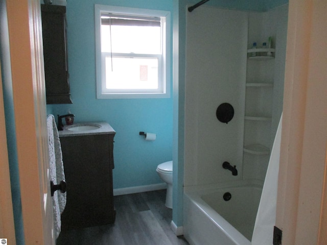 full bath with vanity, shower / tub combination, toilet, wood finished floors, and baseboards