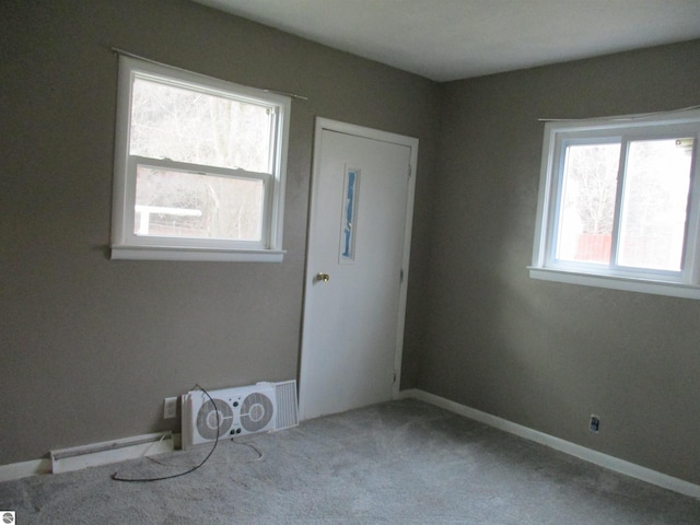 empty room with baseboards, a baseboard radiator, and carpet