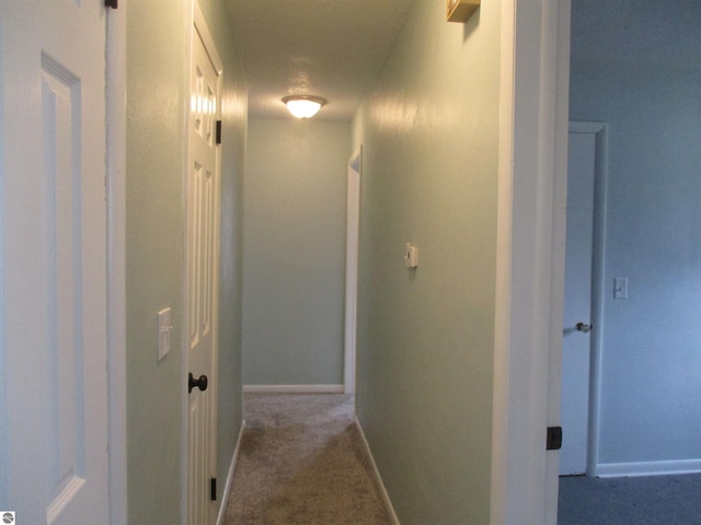 hallway with carpet floors and baseboards