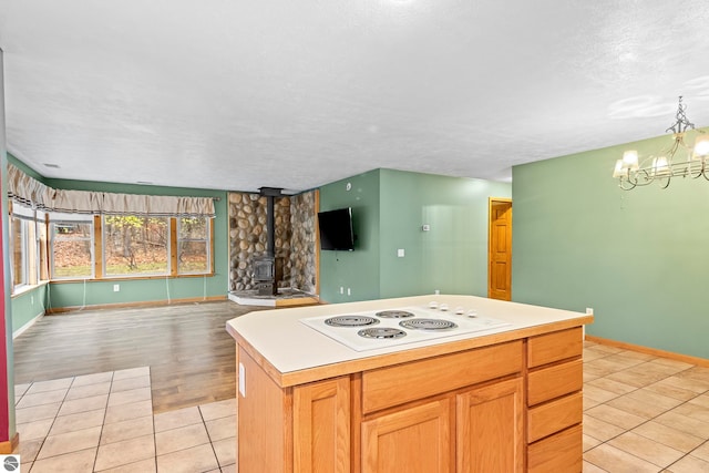 kitchen with a chandelier, light tile patterned floors, open floor plan, a wood stove, and white electric stovetop
