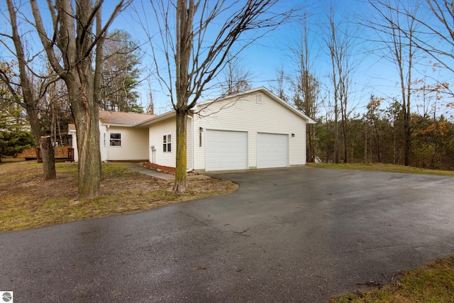 view of side of property with a garage and aphalt driveway