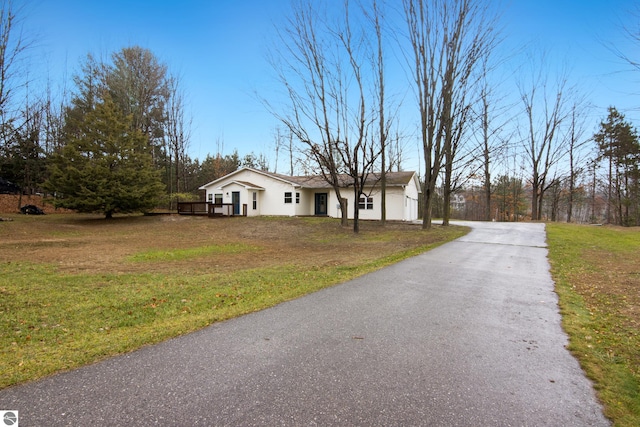 view of front of home with aphalt driveway and a front lawn