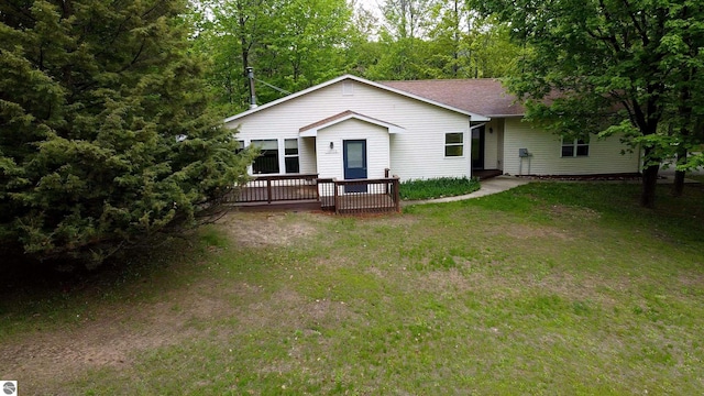 12110 Jonathan Dr, Rapid City, MI 49676 - view of front of home featuring a wooden deck, a front yard, and roof with shingles