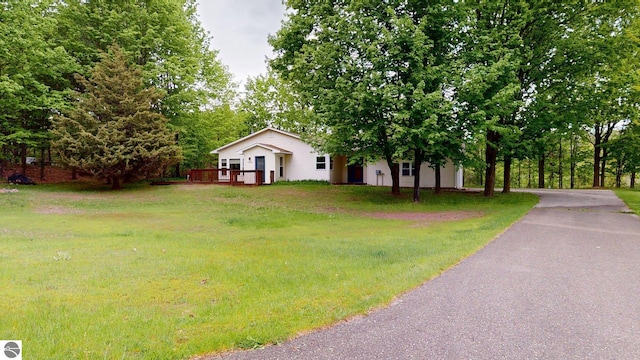 12110 Jonathan Dr, Rapid City, MI 49676 - view of front of property featuring a front lawn and a wooden deck