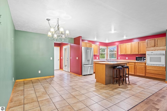 kitchen featuring a center island, light countertops, appliances with stainless steel finishes, a kitchen breakfast bar, and a chandelier