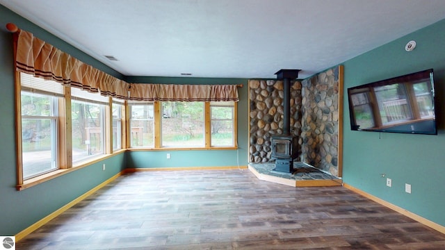 12110 Jonathan Dr, Rapid City, MI 49676 - unfurnished living room with baseboards, a wood stove, and wood finished floors