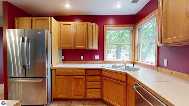 12110 Jonathan Dr, Rapid City, MI 49676 - kitchen featuring appliances with stainless steel finishes, a sink, light countertops, brown cabinetry, and light tile patterned flooring
