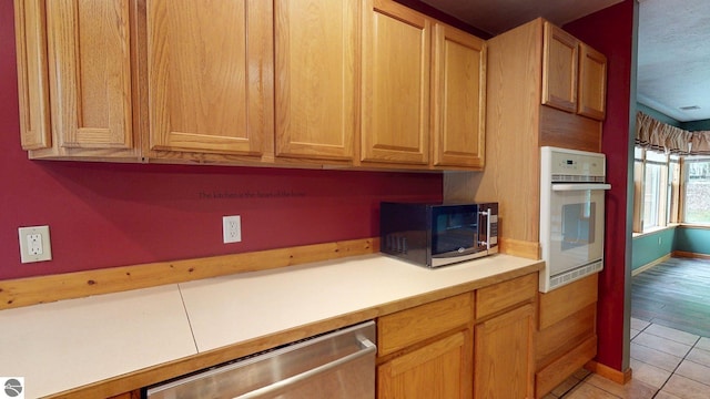 12110 Jonathan Dr, Rapid City, MI 49676 - kitchen with stainless steel appliances, light countertops, light tile patterned floors, and baseboards
