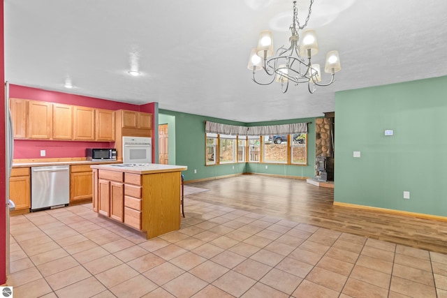 kitchen with an inviting chandelier, open floor plan, light countertops, light wood finished floors, and stainless steel appliances