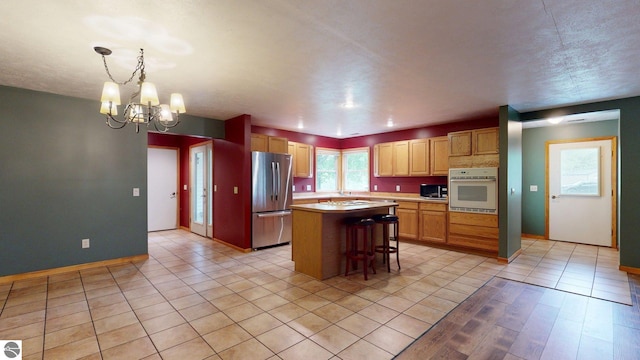 12110 Jonathan Dr, Rapid City, MI 49676 - kitchen featuring appliances with stainless steel finishes, a chandelier, light countertops, a breakfast bar, and a kitchen island