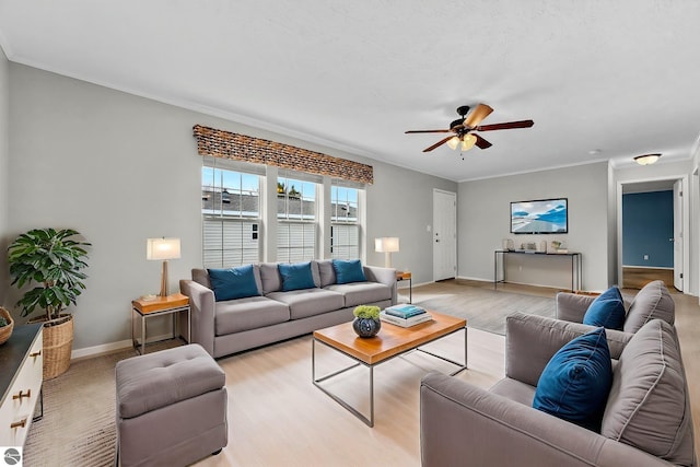 living room featuring crown molding, ceiling fan, baseboards, and light wood-type flooring